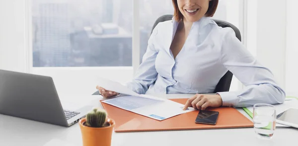 Lächelnde Geschäftsfrau, die im Büro arbeitet und Diagramme checkt — Stockfoto