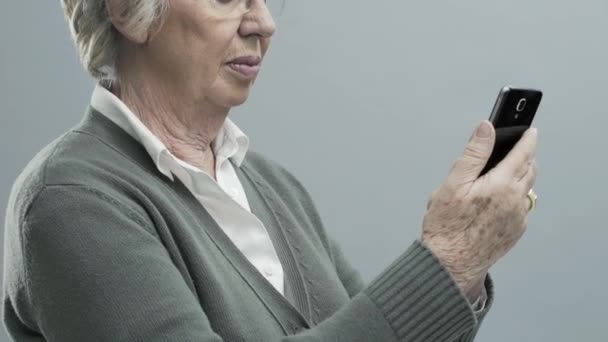 Улыбающаяся пожилая леди с помощью сенсорного экрана смартфона — стоковое видео