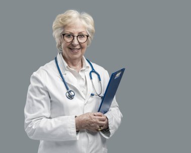 Poz ve gülümseyerek emin üst düzey kadın doktor