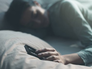 Bir kadın uyuyor ve telefonunu tutuyor.