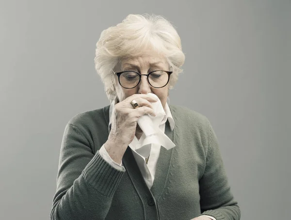 Больная старшая леди, сморкающаяся — стоковое фото