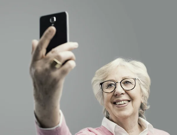 Mujer mayor feliz tomando selfies con su smartphone — Foto de Stock