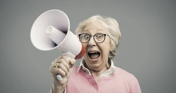 Senhora idosa alegre gritando em um megafone — Fotografia de Stock