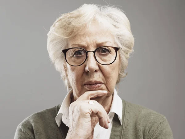 Pensive senior woman thinking with hand on chin
