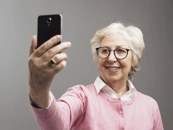 Mujer mayor feliz tomando selfies con su smartphone —  Fotos de Stock