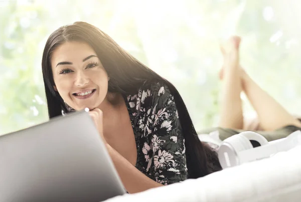 Frau liegt auf Bett und verbindet sich mit ihrem Laptop — Stockfoto