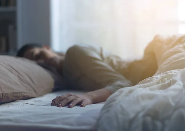 Jeune femme dormant seule dans son lit — Photo