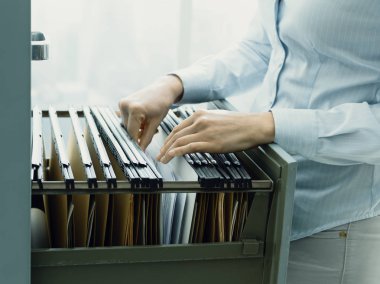 Office clerk searching files in the filing cabinet clipart