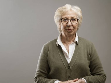 Dingin yaşlı kadın gri arka planda poz