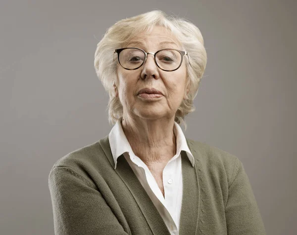 Selbstbewusste Seniorin posiert auf grauem Hintergrund — Stockfoto