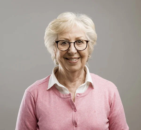 Glückliche Seniorin posiert auf grauem Hintergrund — Stockfoto