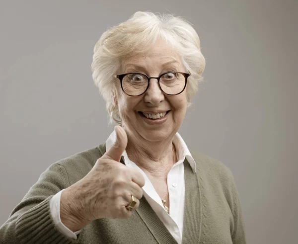 Cheerful senior lady giving a thumbs up