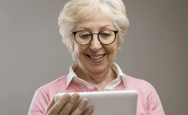 Felice signora anziana utilizzando un tablet digitale — Foto Stock