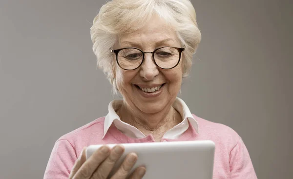 Feliz señora mayor usando una tableta digital —  Fotos de Stock