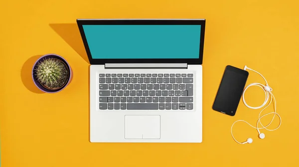 Laptop e smartphone em uma mesa amarela brilhante — Fotografia de Stock