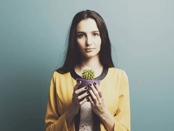Молодая женщина держит горшок с кактусом — стоковое фото