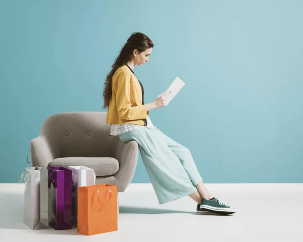 Woman shopping and reading a fashion magazine — Stockfoto