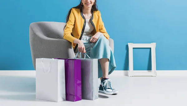 Lycklig kvinna sitter på en fåtölj efter shopping — Stockfoto