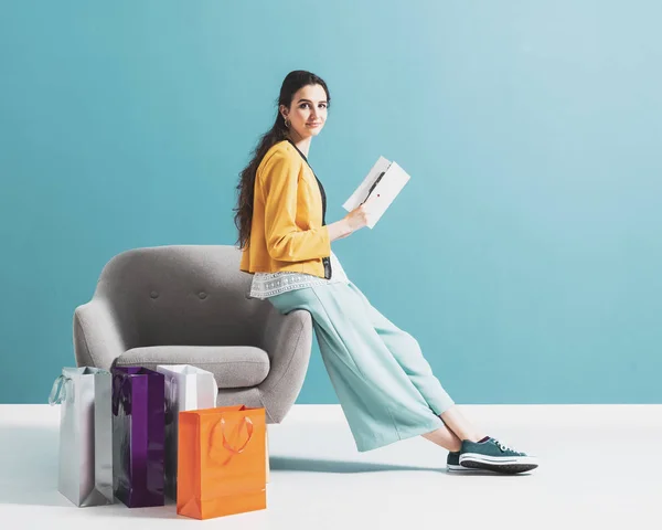 Woman shopping and reading a fashion magazine — Stockfoto