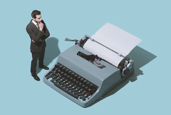 Homem à espera de novas ideias ao lado de uma máquina de escrever — Fotografia de Stock