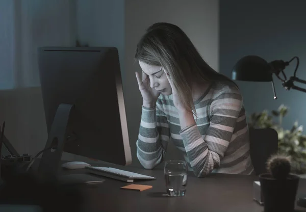 Уставшая женщина работает за столом поздно ночью — стоковое фото