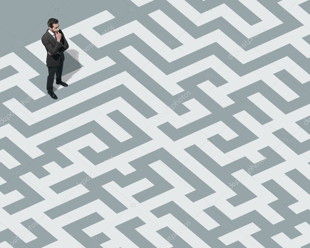 Businessman standing on a maze and searching for a way out