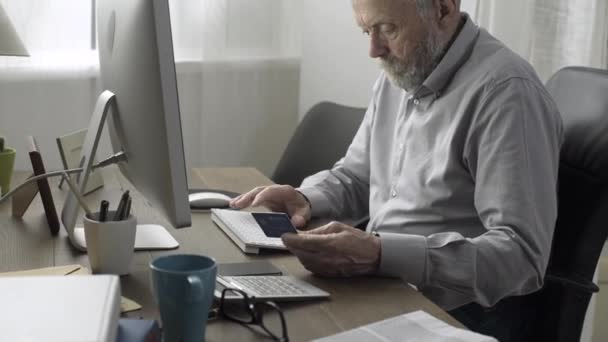 Старший мужчина делает покупки онлайн с помощью своей кредитной карты — стоковое видео