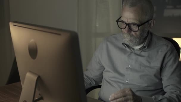 Hombre mayor cansado trabajando con su computadora por la noche — Vídeo de stock