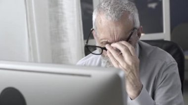 Bilgisayarla çalışan ve yorgun hisseden kıdemli adam