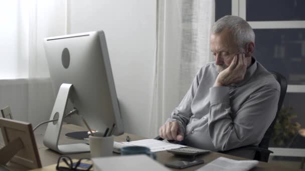 Старший чоловік перевіряє домашні фінанси та рахунки — стокове відео