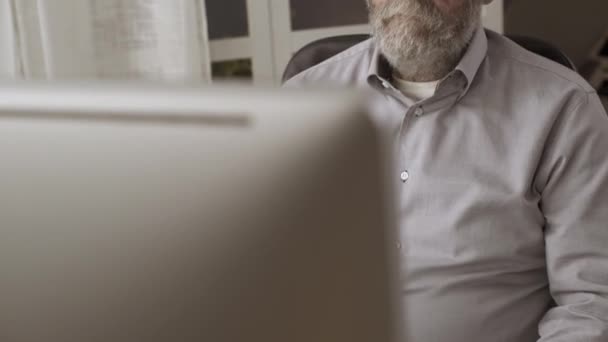 Hombre mayor trabajando con su computadora y sintiéndose cansado — Vídeos de Stock