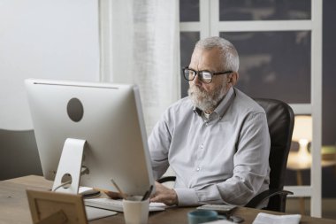 Evde bilgisayarı ile bağlanan kıdemli adam