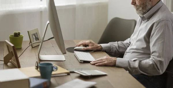 Homem sênior usando seu computador em casa — Fotografia de Stock