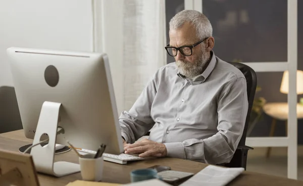 Hombre mayor conectándose con su computadora en casa — Foto de Stock