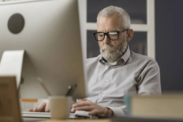 Starszy mężczyzna łączący się z komputerem w domu — Zdjęcie stockowe