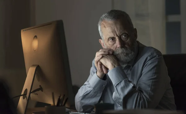 Zkušený starší muž, který v noci pracuje se svým počítačem. — Stock fotografie