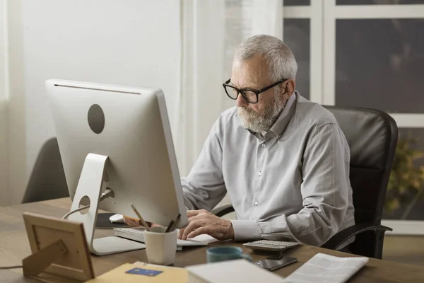 Senior man ansluter med sin dator hemma — Stockfoto