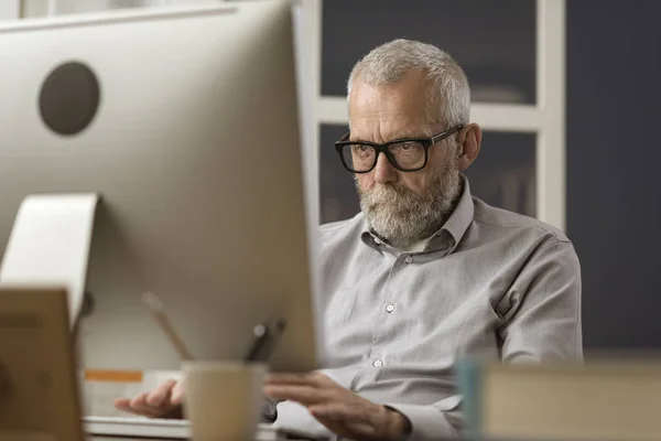 Homem sênior se conectando com seu computador em casa — Fotografia de Stock