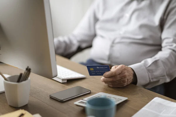 Старший мужчина делает онлайн покупки с помощью кредитной карты — стоковое фото