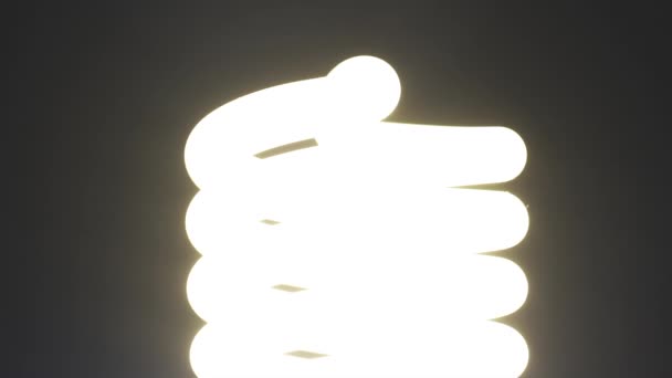 Энергосберегающая лампа включается и выключается на темном фоне — стоковое видео