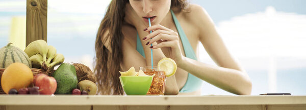 Attractive young woman having a cocktail at the beach