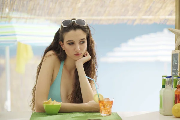 Triste donna sola che beve qualcosa in spiaggia — Foto Stock
