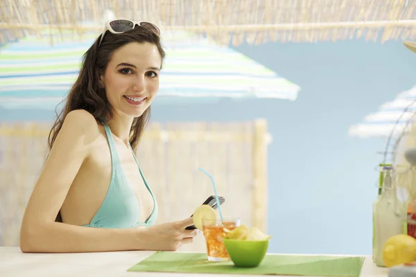 Joven hermosa mujer tomando una copa en la playa — Foto de Stock