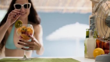 Sahilde meyve salatası yiyen gülümseyen genç kadın