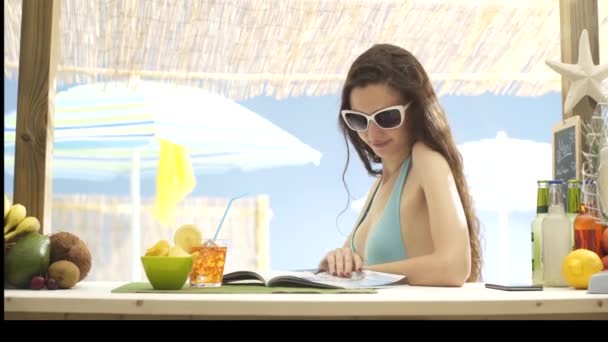 Mulher bonita lendo uma revista na praia — Vídeo de Stock