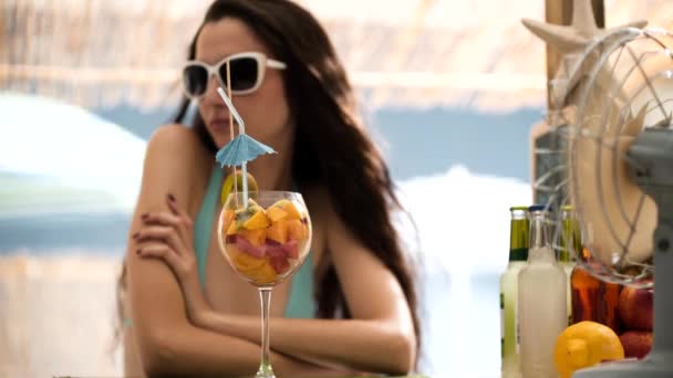 Hermosa mujer tomando una ensalada de frutas en la playa — Vídeos de Stock