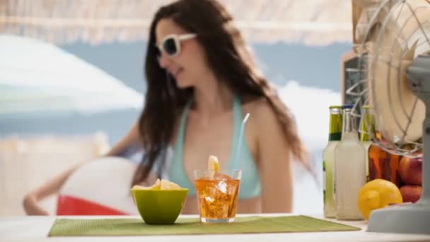 Mooi meisje met een drankje aan de strandbar kiosk — Stockvideo