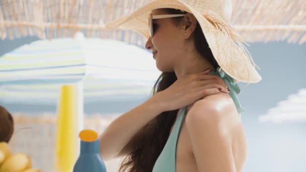 Jonge vrouw op het strand aanbrengen zonnebrandcrème — Stockvideo