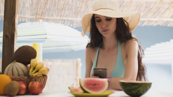 美丽的年轻女子与她的智能手机在沙滩上聊天 — 图库视频影像