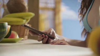 Genç kadın plajda akıllı telefonuyla sohbet ediyor